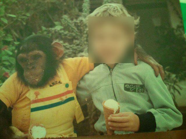 Ein Foto von Schimpansen Linda und einem Kind. Linda hat die Kinderkleidung an und posiert um Touristen anzulocken. Sie hat den Arm um ein Kind gelegt, dessen Gesicht zensiert ist.